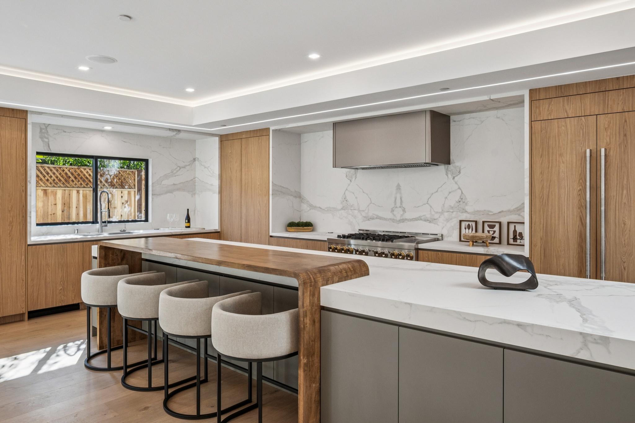 High-end contemporary open kitchen architecture in a Willow Glen custom home, showcasing a dual-layer island design, premium bookmatched stone backsplashes, and bespoke architectural millwork.