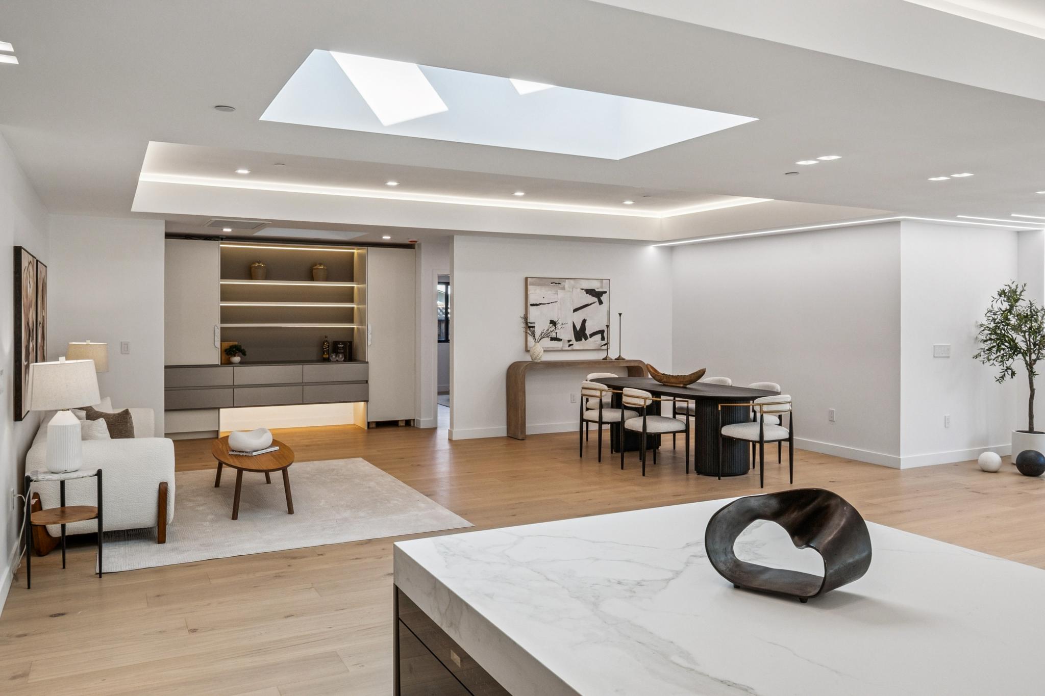 Luxury open-concept dining room design in Willow Glen, San Jose, highlighting a massive architectural skylight, modern minimalist dining table, and premium integrated wet bar cabinetry.