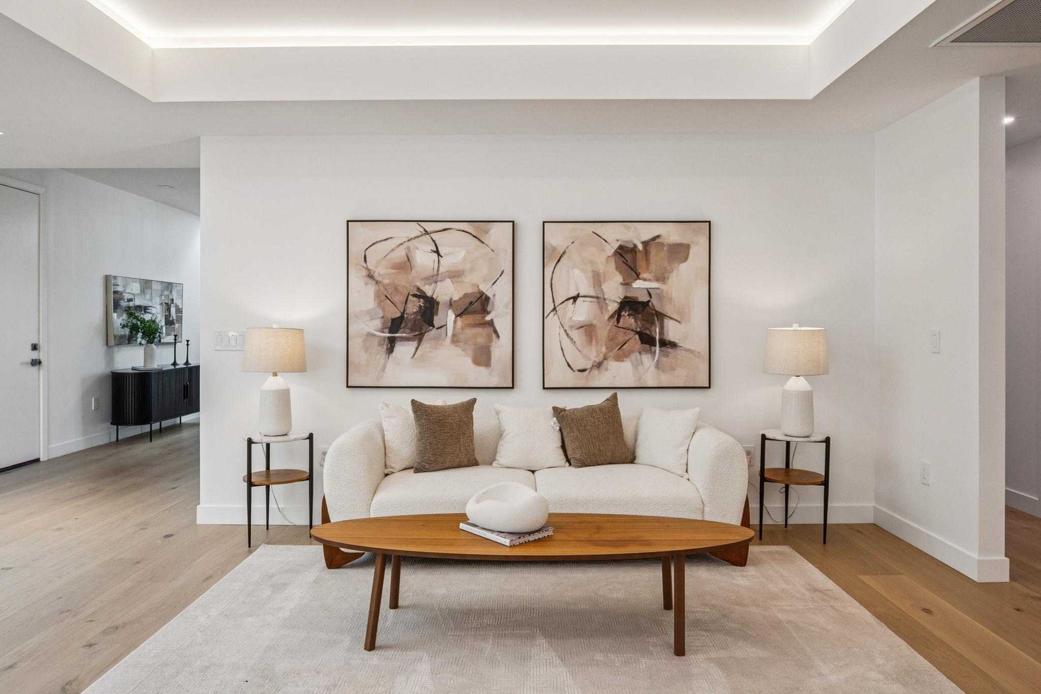 Sophisticated contemporary formal sitting area inside a luxury San Jose residence, showcasing a white bouclé accent sofa, minimalist coffee table, and curated abstract art.