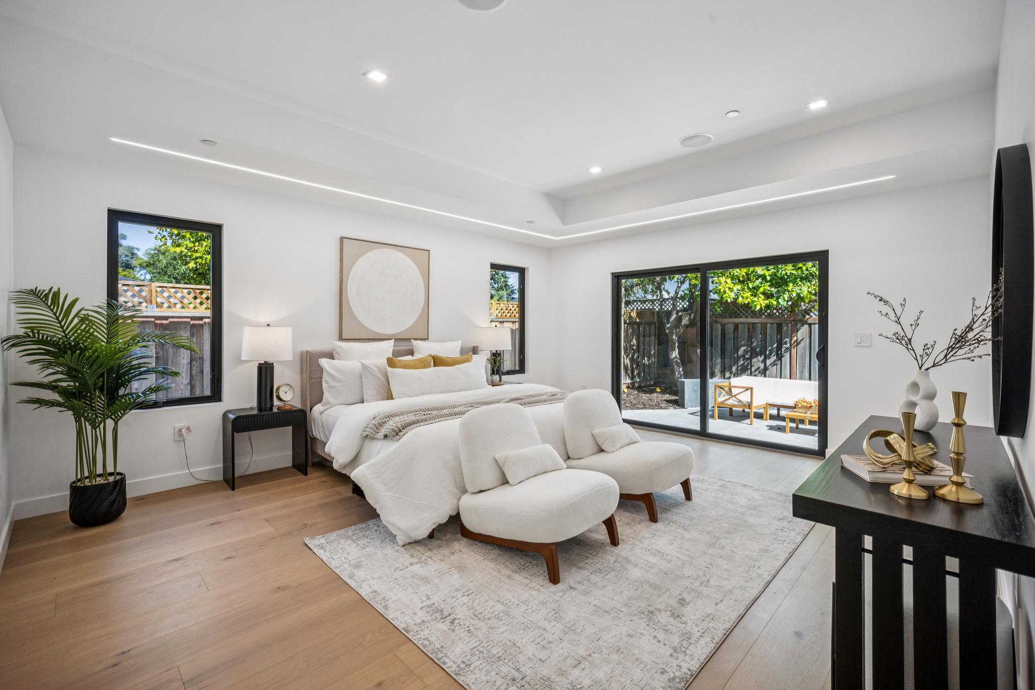 Master bedroom suite in a custom luxury home in San Jose, highlighting a recessed tray ceiling with embedded linear lighting and private patio glass slider doors.
