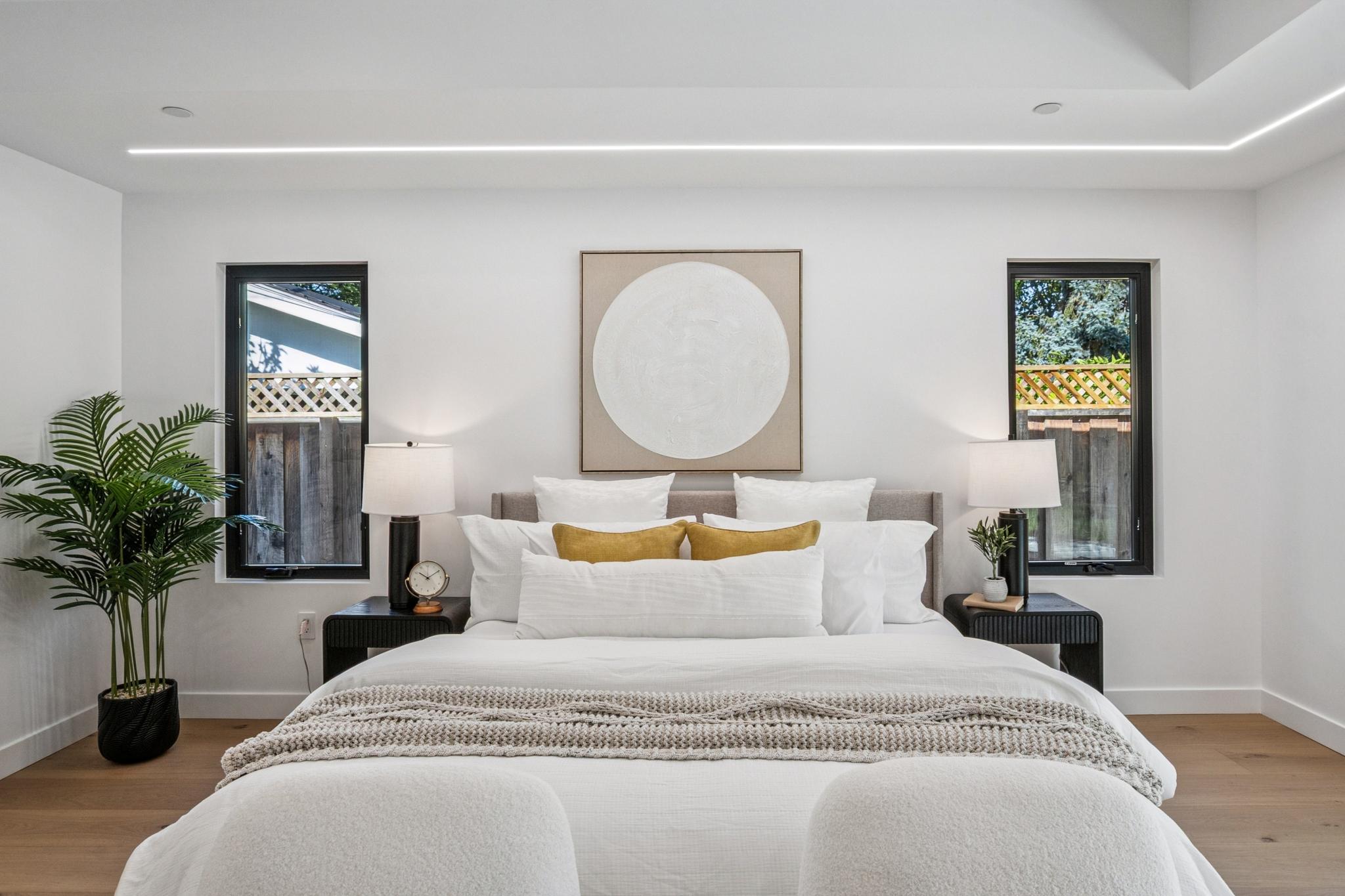 Symmetrical master bedroom architecture in a luxury San Jose custom home, featuring minimalist black-framed windows, modern nightstands, and custom luxury bedding.