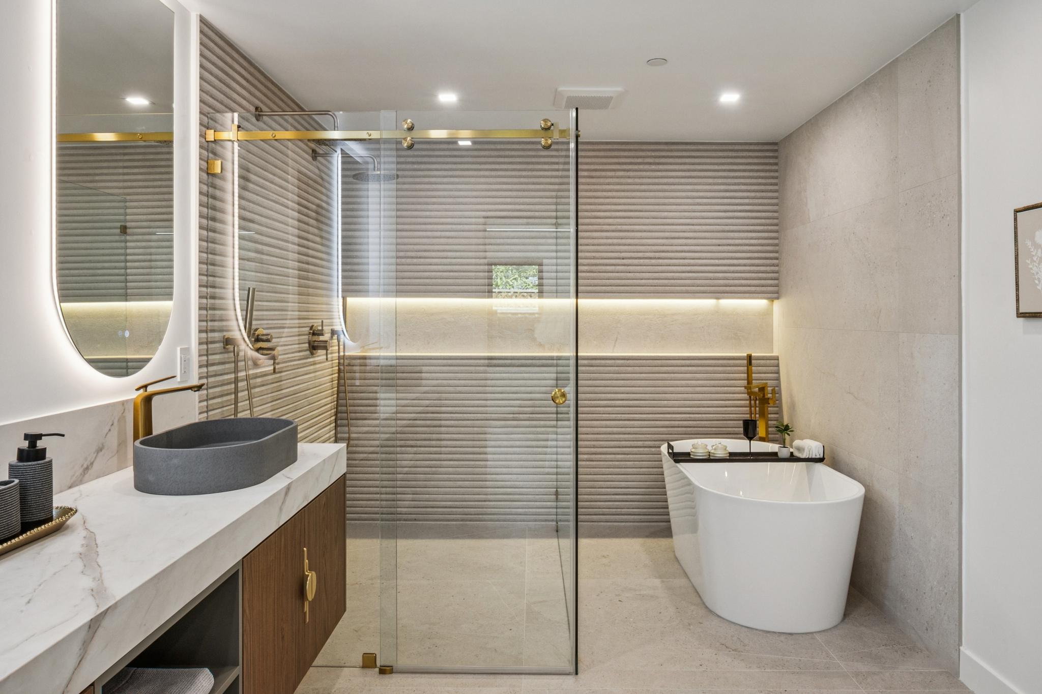 Elite master bathroom spa suite in a Willow Glen custom home, showcasing a standalone soaking tub, premium brushed gold plumbing fixtures, and a zero-threshold glass walk-in shower with textured accent tile.