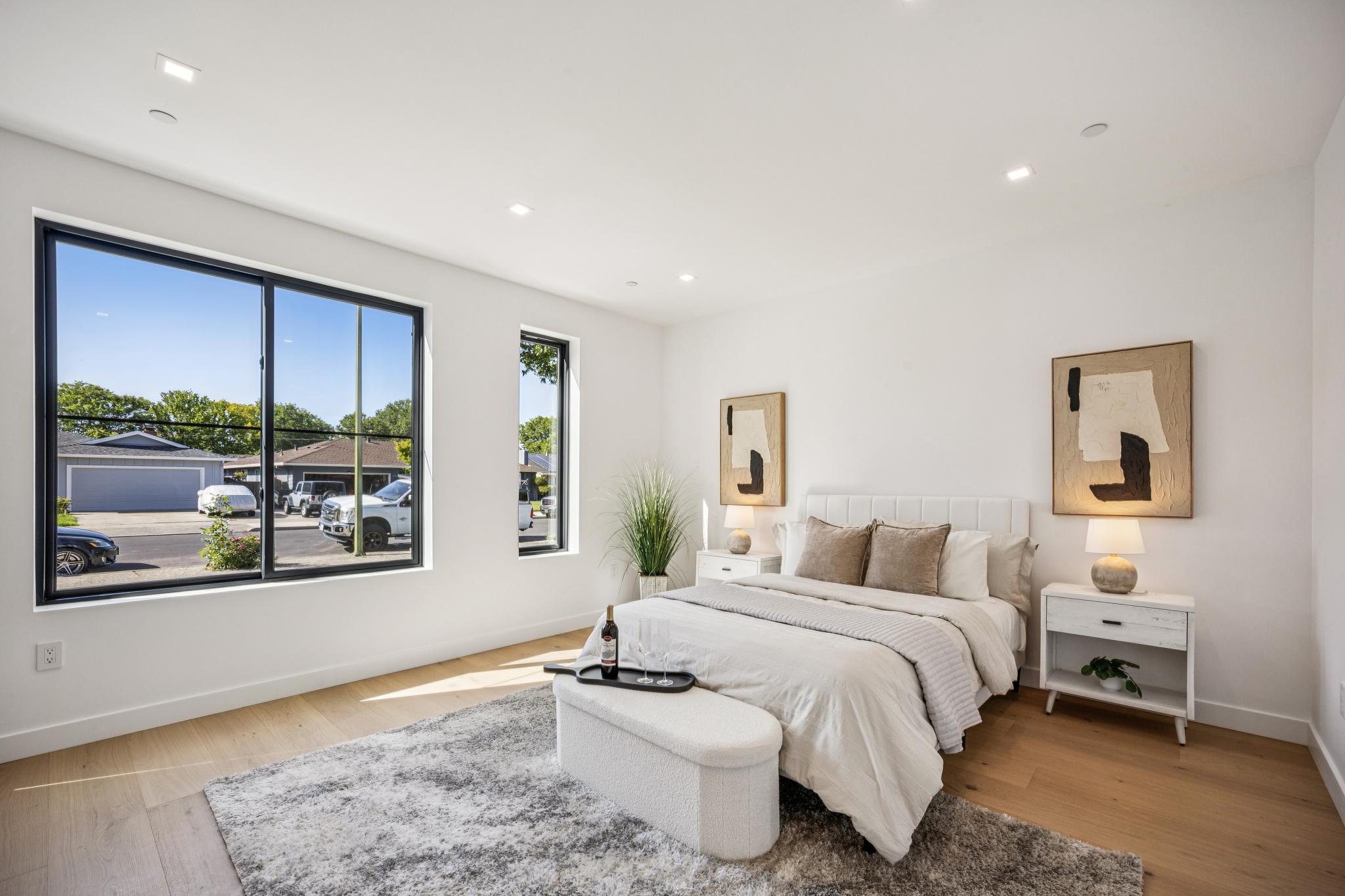 Bright front-facing luxury bedroom in a San Jose modern farmhouse, featuring expansive black-framed windows, premium natural lighting, and bespoke interior styling built by Ritz Builders.