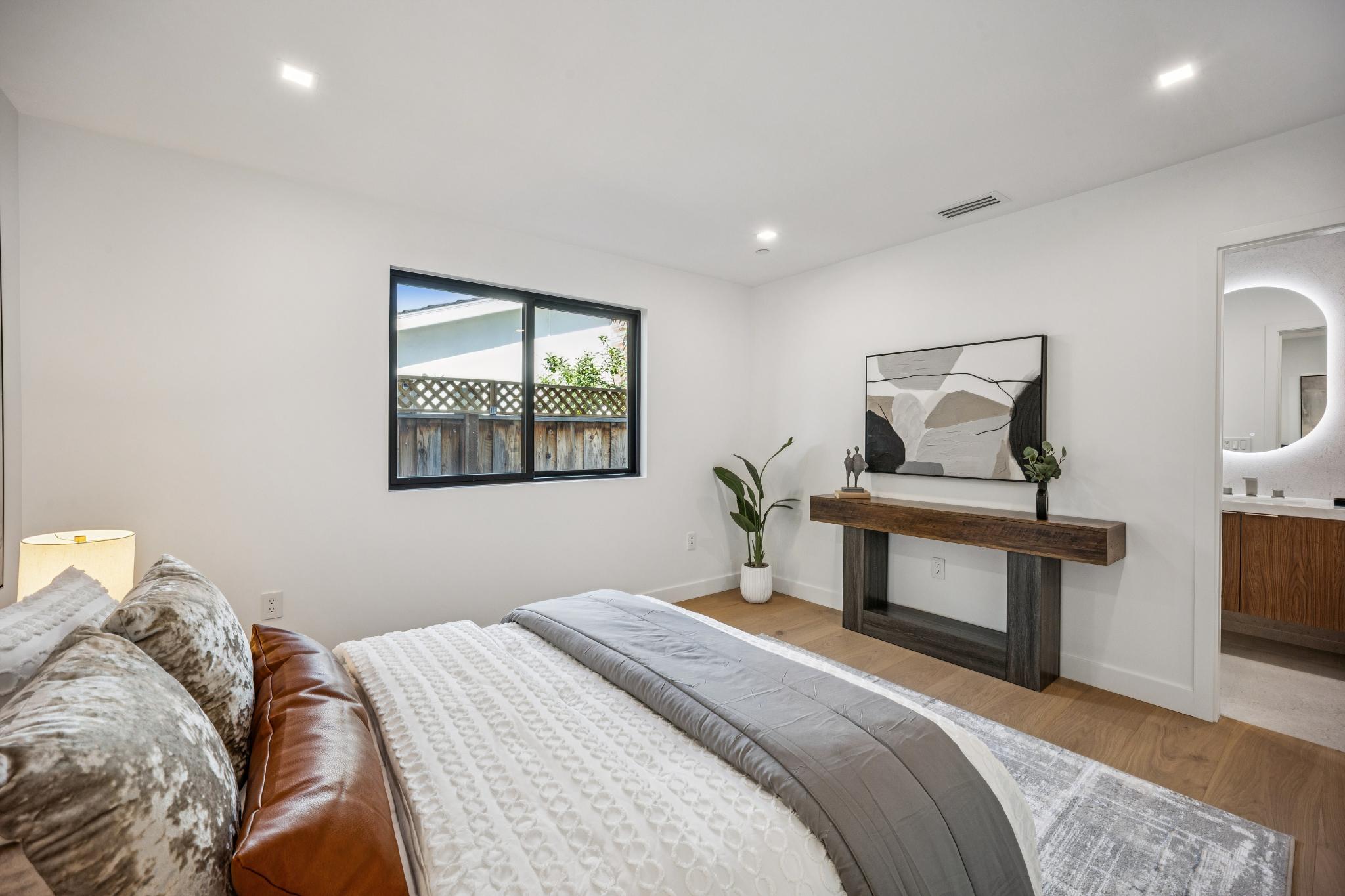 Luxury guest bedroom suite in Willow Glen, San Jose, showcasing a seamless architectural transition into a high-end en-suite bathroom complete with custom millwork and backlit mirrors by Ritz Builders.