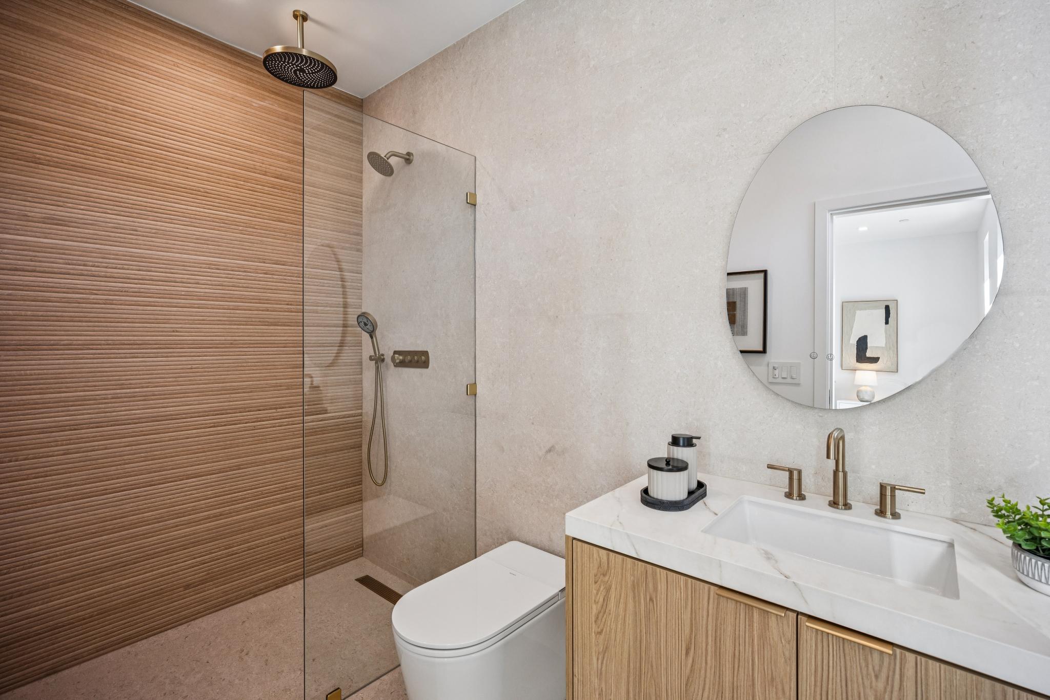 High-end custom bathroom remodel in San Jose, featuring a frameless glass walk-in shower with bespoke 3D ribbed accent tile, premium brass shower hardware, and large-format stone walls executed by Ritz Builders.