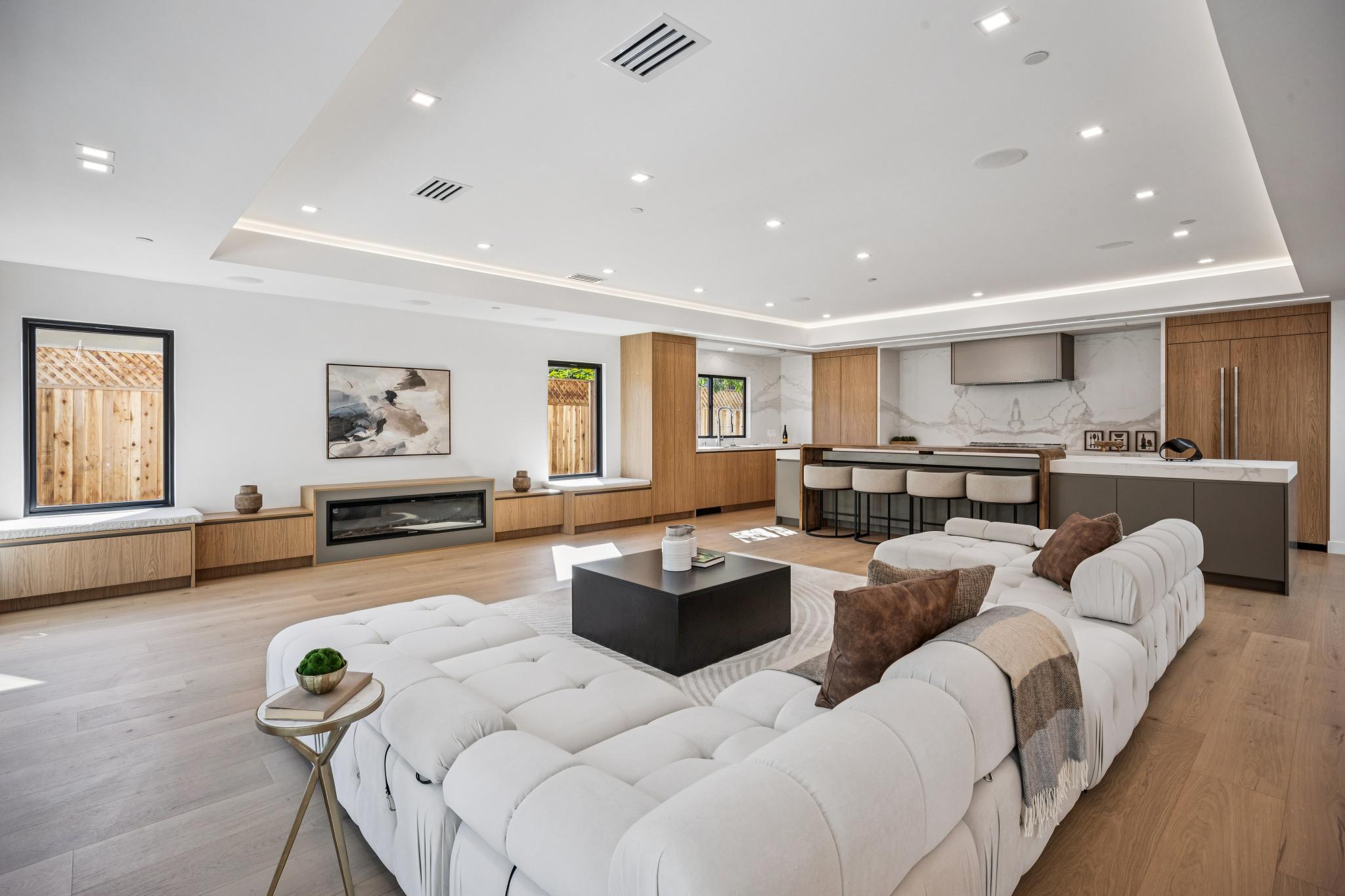 Luxury custom home great room in San Jose, highlighting an expansive open floor plan with hidden LED tray ceiling lighting and a seamless transition to the gourmet kitchen.